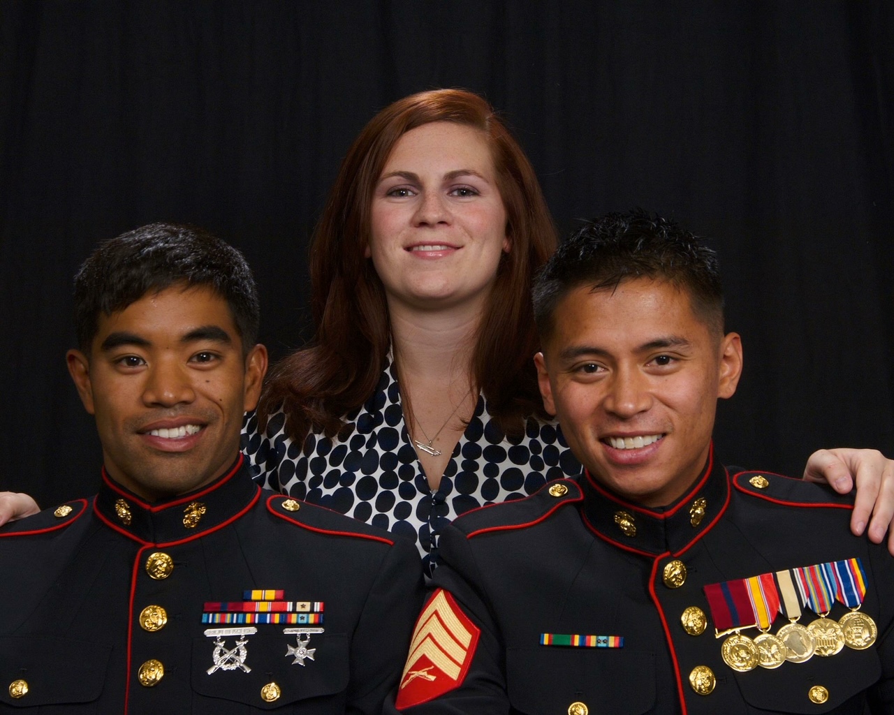 Libby Jamison standing behind two Marines in dress blue uniforms.