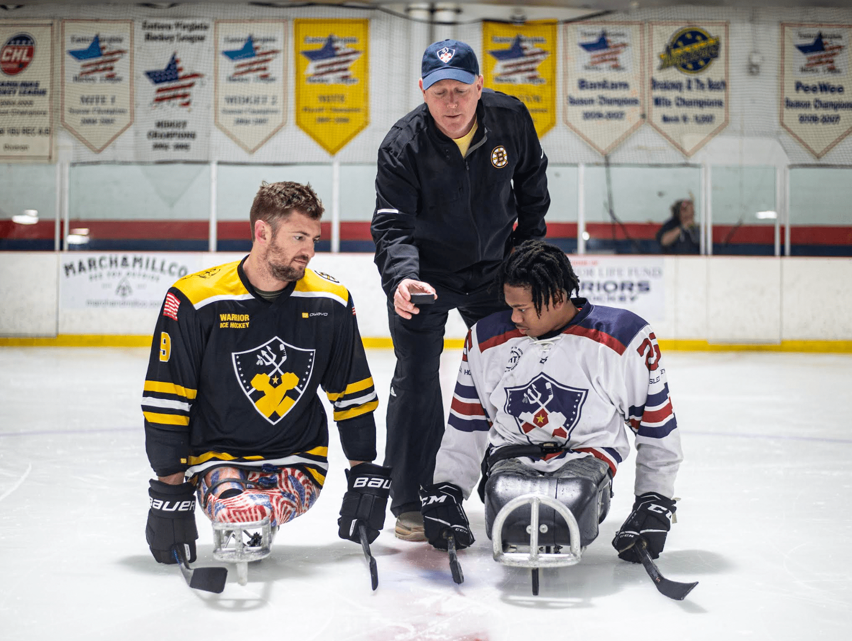Boston Bruins Alumni President Frank Simonetti drops the ceremonial puck between Gold Medal Paralympian Travis Dodson and WFLF Adaptive Athlete Zyree Fuller at the 2022 Sled Hockey Exhibition Game in Virginia Beach.