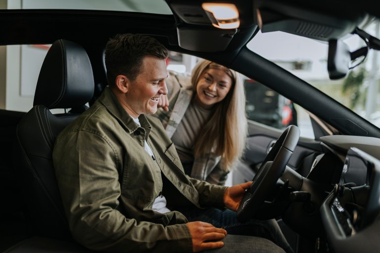 Young couple testing car in car dealership