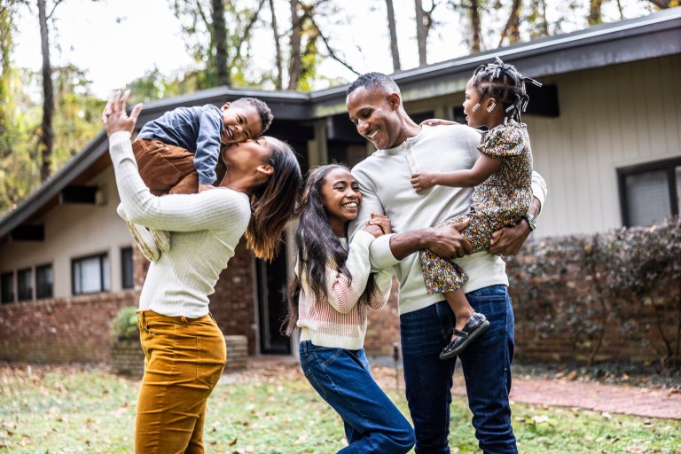 Portrait of family with young children in front of suburban home