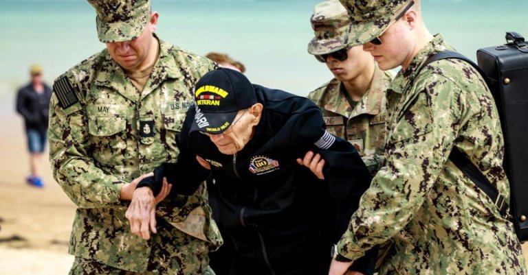 Active Duty sailors help a World War II veteran during a visit to Normandy on the anniversary of D-Day, 2024. (3blmedia)