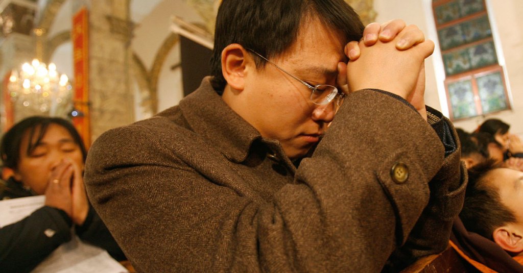 Chinese Catholics pray while a young boy sleeps during Christmas mass at a government approved Catholic church in Beijing, 25 December 2007. China's official Catholic church has installed a new Vatican-approved bishop, the third in a month, state media and a Rome-based religious news agency reported on 22 December as up to an estimated 10 million "underground" Chinese Catholics pledge allegiance to the pope, worship in unofficial churches and are often subject to police and government harassment. AFP PHOTO/TEH ENG KOON (Photo credit should read TEH ENG KOON/AFP via Getty Images)