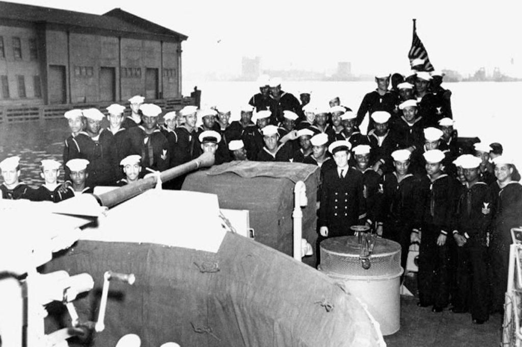 PC-1264's enlisted complement on the fantail, at the time of her commissioning ceremonies, 25 April 1944, at New York City. There are three white Petty Officers, only ones assigned at that time, in the front ranks (two on left - head and shoulders only, one slightly right of middle). The white Petty Officer on the far left is BM1c Donald Briggs from New Jersey. Also note barrel of 40mm single gun mount in left foreground.