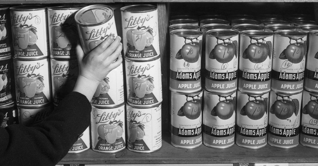 ebruary 1943: Someone reaches for a can of orange juice from a grocery shelf during World War II. Cards indicating 'Ration Points Required' for various canned foods helped America's wartime marketers in using War Ration Book Two.