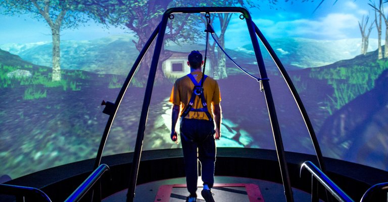 A Traumatic Brain Injury (TBI) patient walks through a virtual reality scenario at the Computer Assisted Rehabilitation Environment (CAREN) Laboratory at National Intrepid Center of Excellence (NICoE) at Walter Reed National Military Medical Center in Bethesda, Md., March 20, 2017. The patient is attached to a safety harness and walks on a treadmill on a platform that moves and rotates in conjunction with movements of the projected environment. Motion capture cameras track the patient’s movements via reflective markers that are applied to the patient and supply data on physical deficits to physical therapists. (U.S. Air Force photo by J.M. Eddins Jr.)