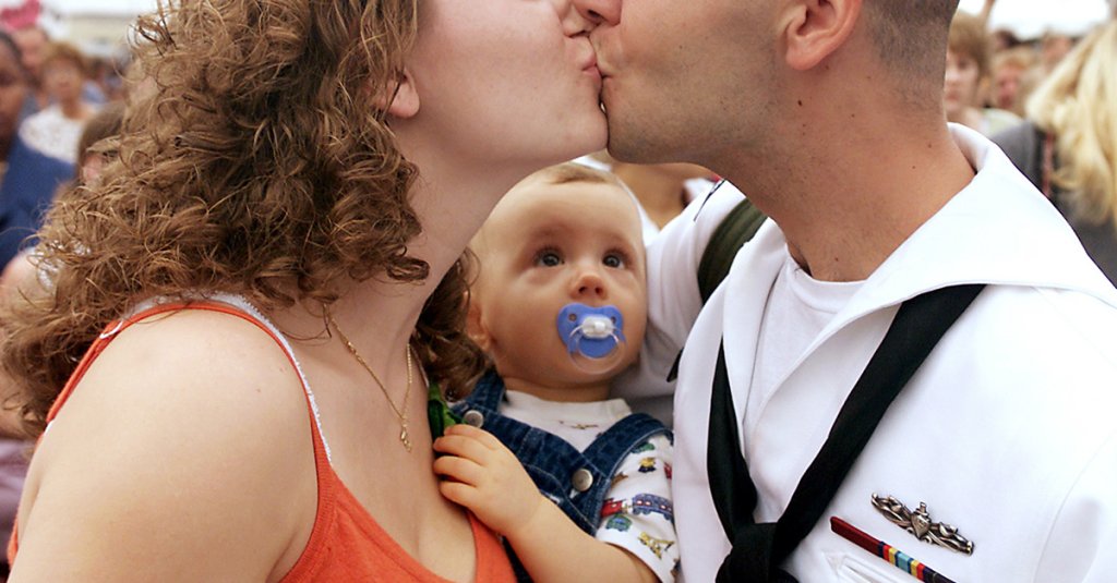 "Yeah, that's my dad," little Michael Standfill (center) seems to say as he intently watches his father Petty Officer 2nd Class Michael Standfill kiss his wife Terri during their reunion on the pier in Norfolk, Va., on Aug. 18, 2000. Michael's father, who is a Navy operations specialist, just returned from six-month deployment to the Mediterranean Sea and Persian Gulf aboard the USS Mahan (DDG 72). The Mahan was one of nine ships assigned to the USS Dwight D. Eisenhower Carrier Battle Group which enforced no-fly zones over the former Yugoslavia and Southern Iraq. (DoD photo by Petty Officer 1st Class Martin Maddock, U.S. Navy. (Released)
