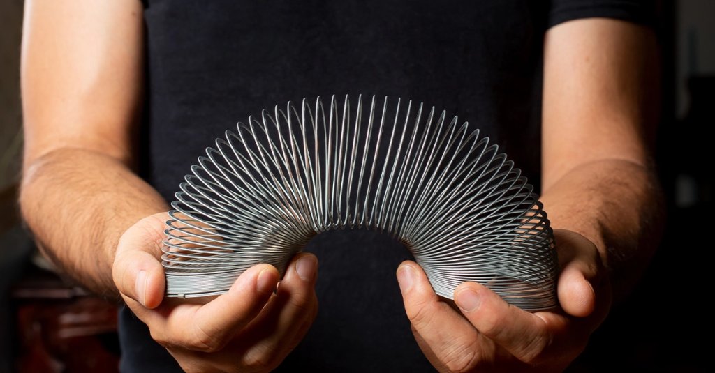 A view of a person holding a Slinky toy in the hands.