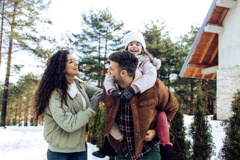 Little girl and her parents enjoying winter vacation on the mountain.