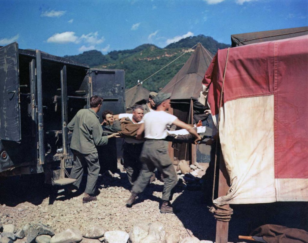 US Army medics move a wounded soldier on a stretcher from a 568th Medical Ambulance Company ambulance into a tent for treatment at the 8225th Mobile Army Surgical Hospital (MASH), Korea, September 1, 1951.