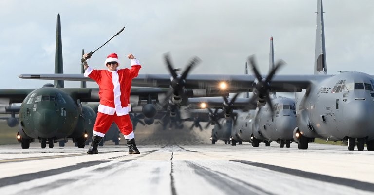 Santa Claus poses in front of multinational aircraft during Operation Christmas Drop 2024 at Andersen Air Force, Guam, Dec. 14, 2024. Events like OCD 2024 allow participating nations an opportunity to provide assistance to remote populations while also offering the ability to maintain preparedness for real-world emergencies. (U.S. Air Force Photo by Airman 1st Adasha Williams)