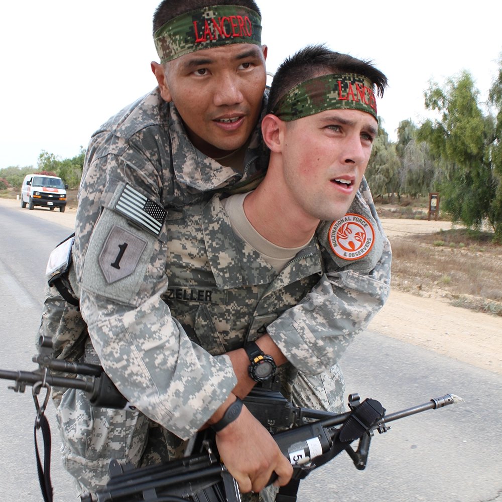 A soldier deployed to Egypt as part of Task Force Sinai carries his battle buddy the last 100 meters across the finish line