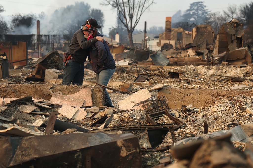 Khaled Fouad (L) and Mimi Laine (R) embrace as they inspect a family member's property that was destroyed by Eaton Fire on January 09, 2025 in Altadena, California.