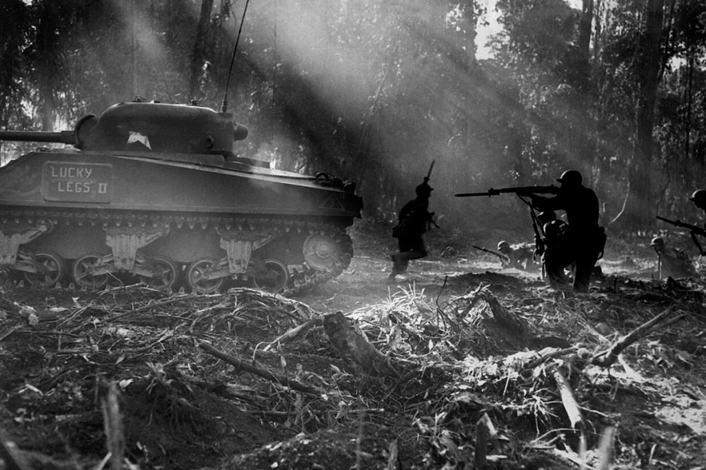 An American infantryman from Company F from the 129th Infantry Regiment, 37th Infantry Division of XIV Corps, United States Army, fires his M1 Garand semi-automatic rifle with fixed bayonet as an M4 (75) Sherman tank nicknamed Lucky Legs II from the 754th Tank Battalion moves up in support infantry weapons world War II M1 garand army