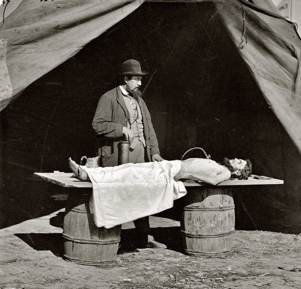 Dr. Richard Burr, an embalming surgeon in Frederick, Va., is shown embalming a soldier recovered from the battlefield. Embalming tables were not usually available in the field, so he used a door placed over two large barrels. Photo courtesy of the National Museum of Civil War Medicine.