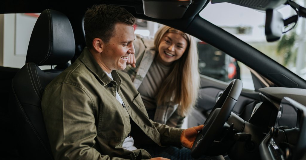 Young couple testing car in car dealership