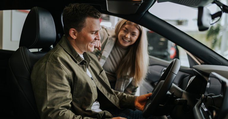 Young couple testing car in car dealership